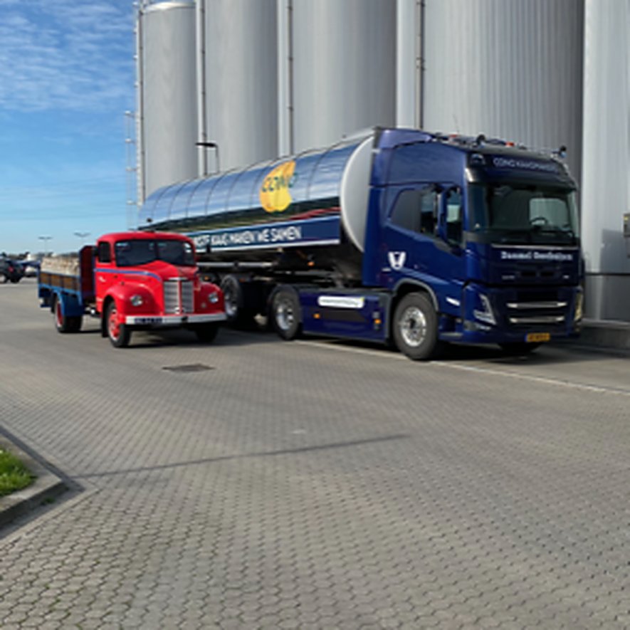 Een vrachtwagen uit de jaren vijftig naast een tankwagen van Danmel bij de fabriek